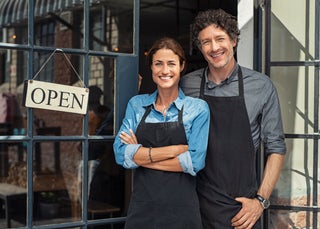 Business owners stand next to open sign