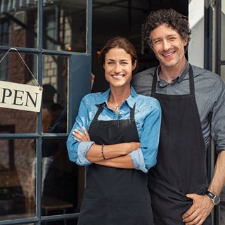 Business owners stand next to open sign