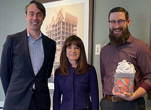 Employee holds excellence award next to management team