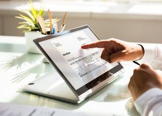 Finger pointing at invoice on computer screen