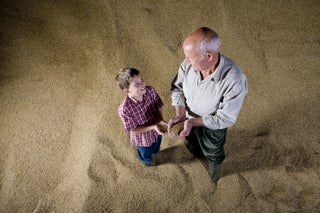 Kid stands with grandpa in pile of grain