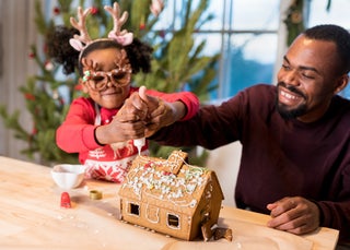 Dad and daughter decorating gingerbread house