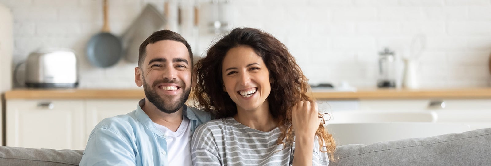 Two people sit on couch together smiling