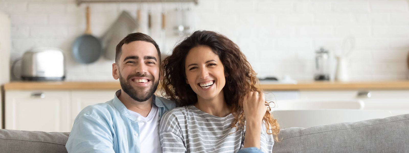 Two people sit on couch together smiling