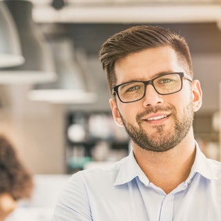 businessman smiles with coworkers in the background