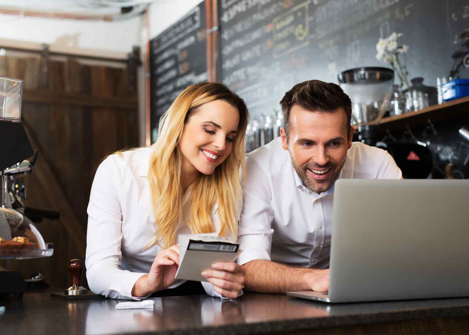 Two business owners and computer in coffee shop