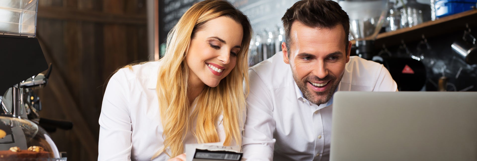 Two business owners and computer in coffee shop