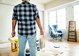 Man holding paint bucket and roller brush