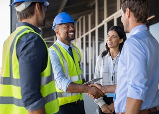 Workers in hard hats shake hands