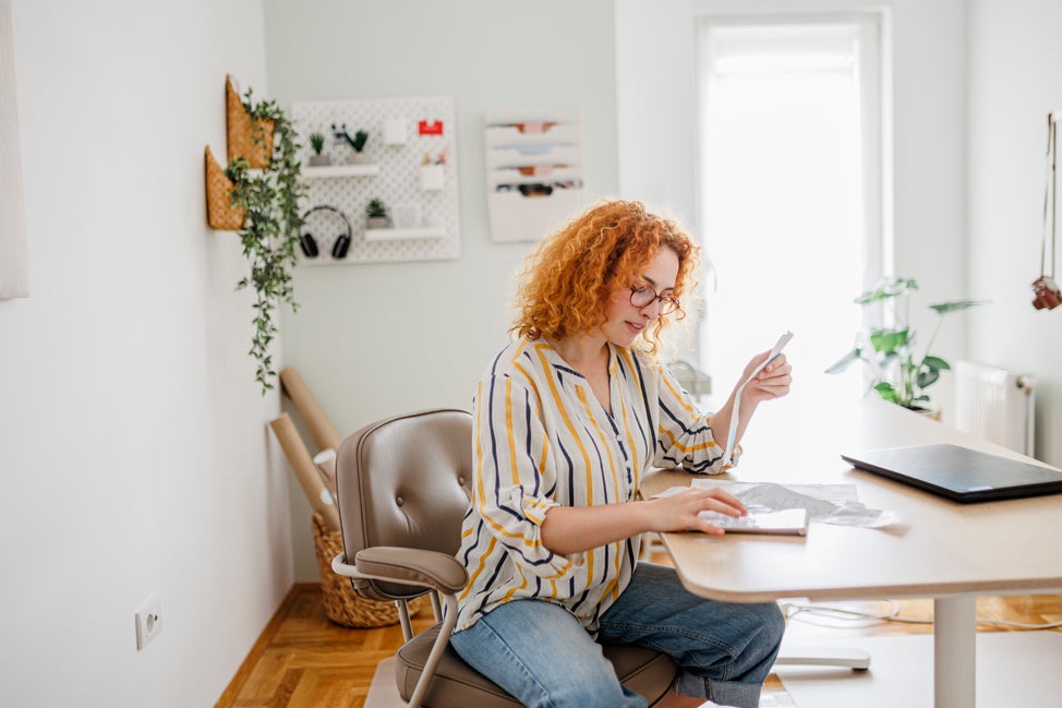 Woman sits at desk calculating finances