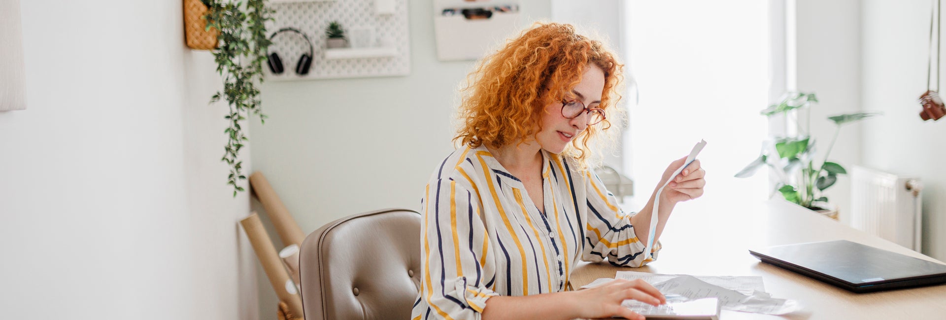 Woman sits at desk calculating finances