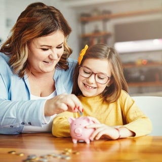 Mom & Daughter put coins in piggy bank