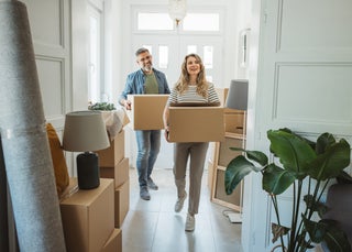 Man and woman carry boxes into new house