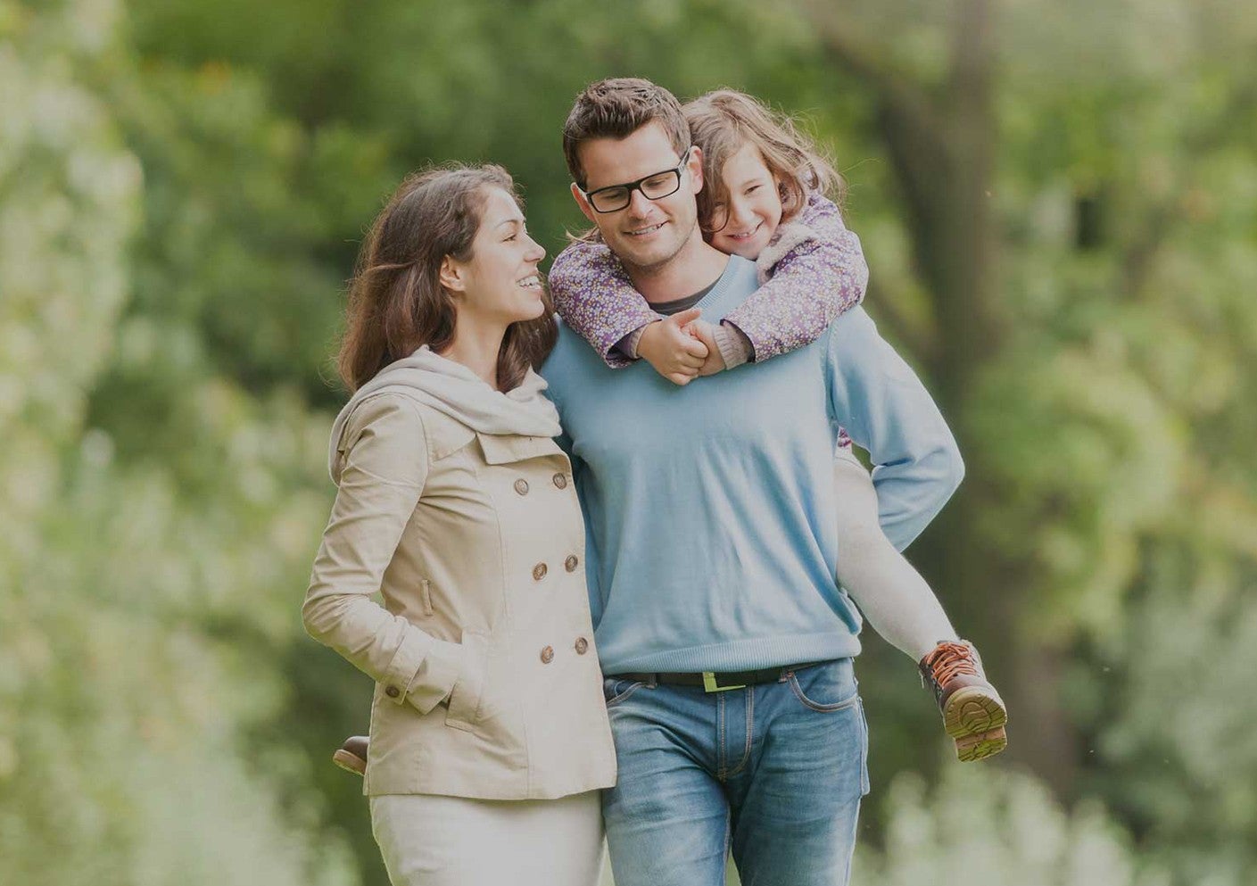 Father walks next to wife while carrying daughter on his back