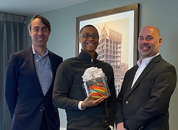 Employee holds excellence award next to management team