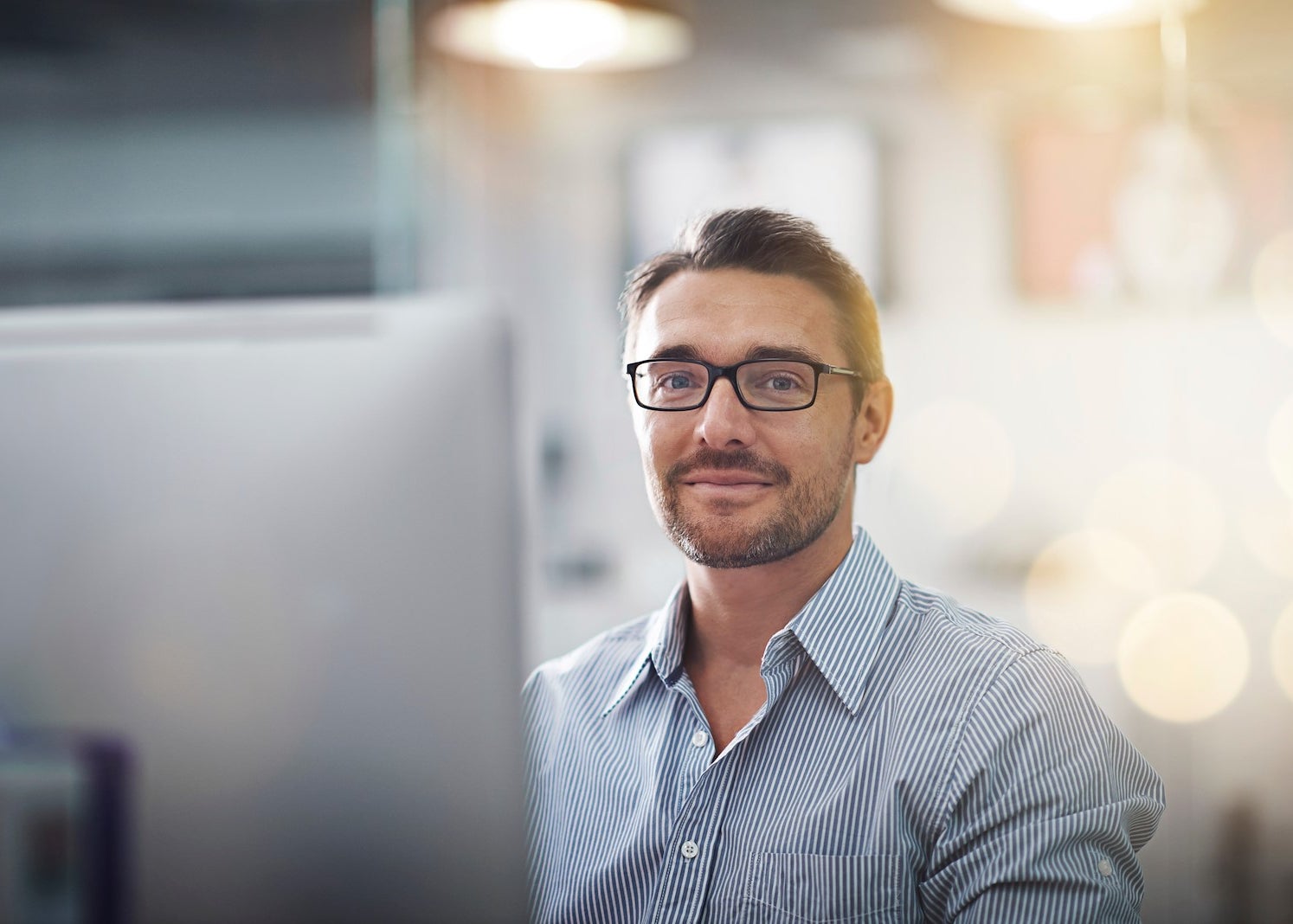 Man sits behind computer smiling