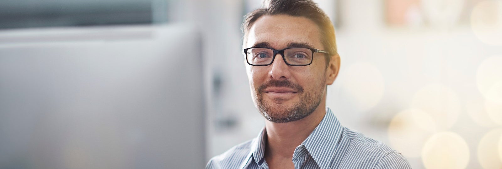 Man sits behind computer smiling