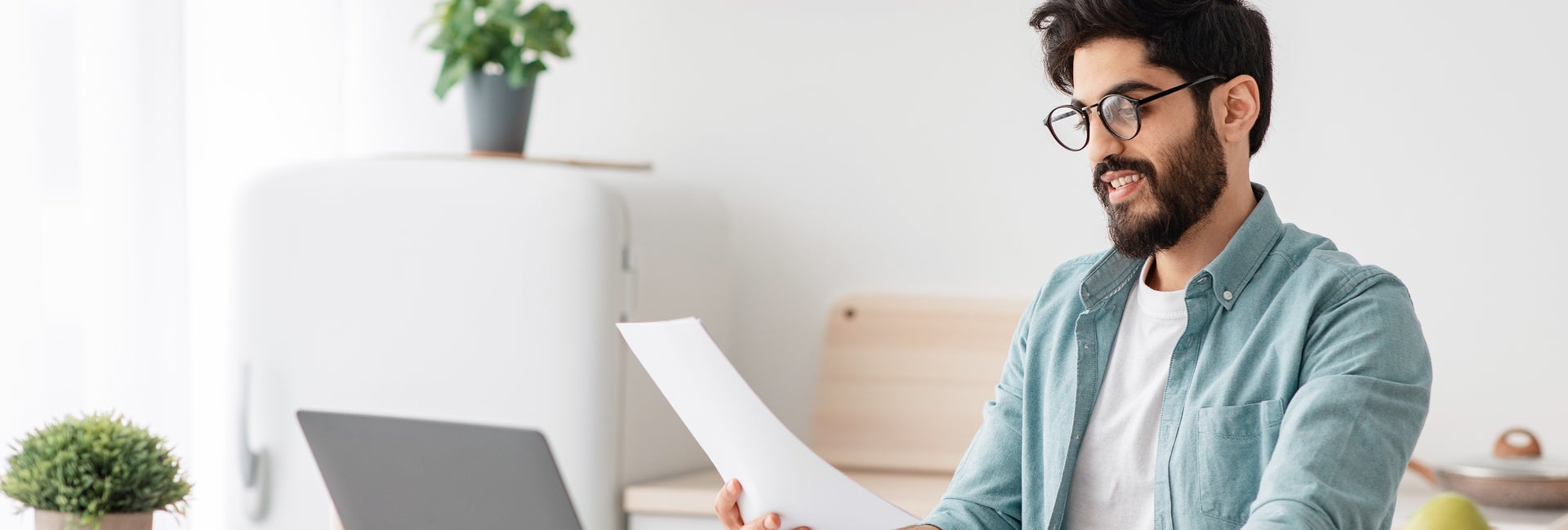 Man looks at bank statement with calculator and computer