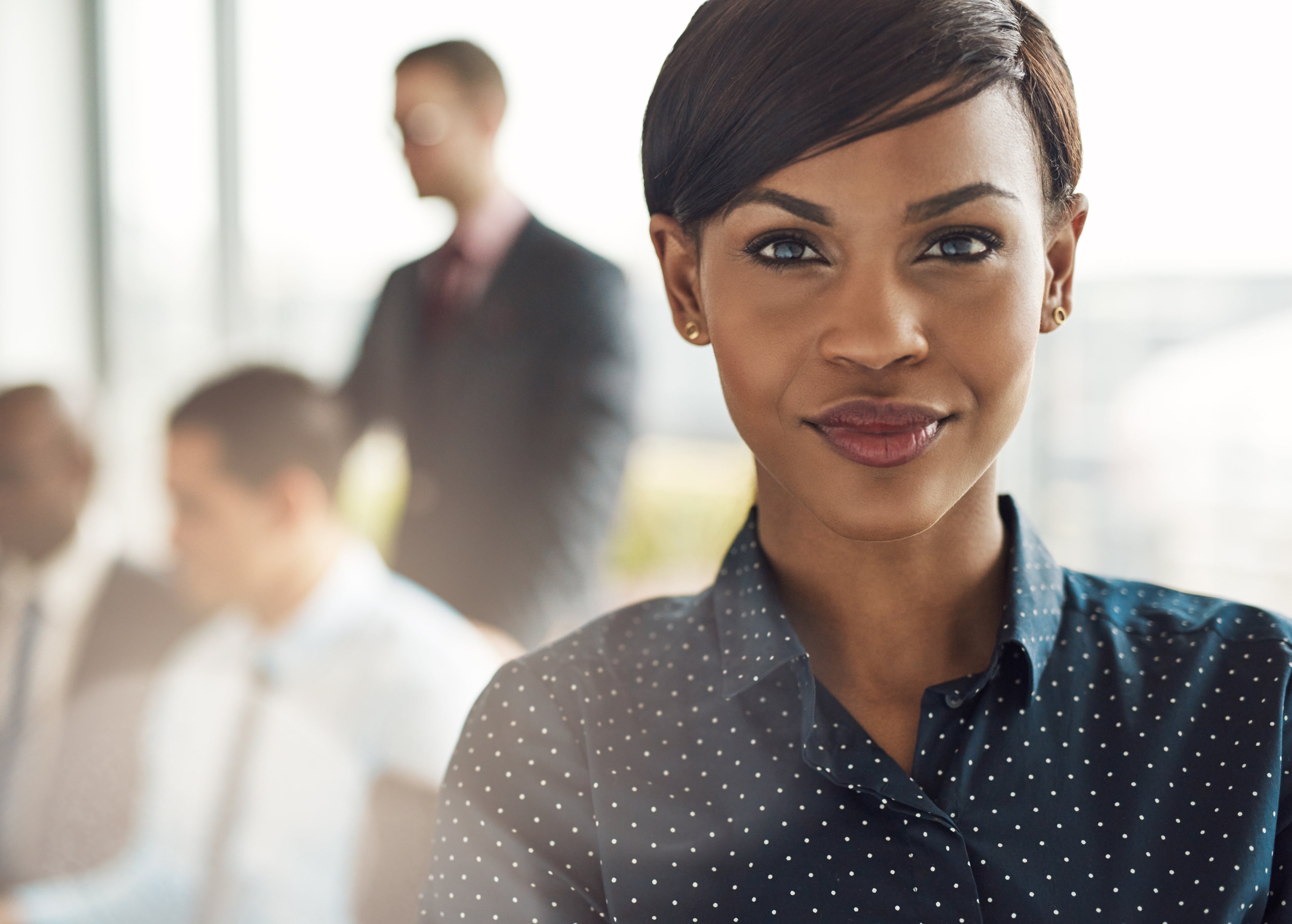 Woman smiles with coworkers in background