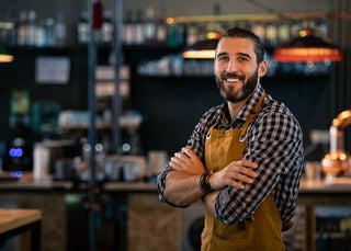 Man smiling in front of a bar