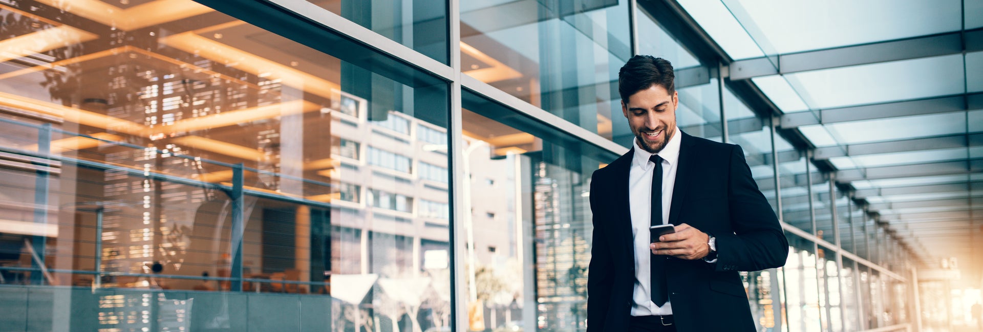 Businessman looks at phone while walking