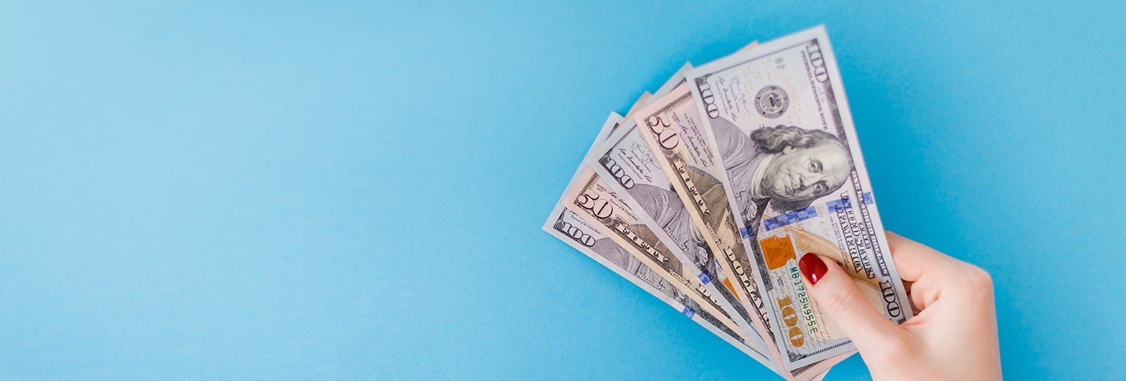 Hand holding large amounts of cash