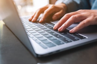 Hands typing on a laptop