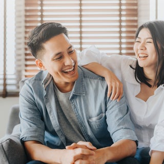 Couple laughing while sitting on couch