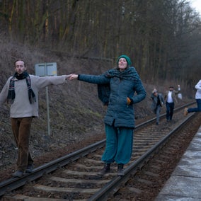 The actors walk down train tracks.