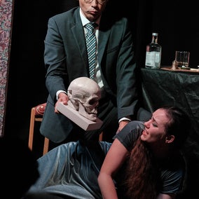 Dr. Kolenaty threatens Emilia Marty with a skull.
