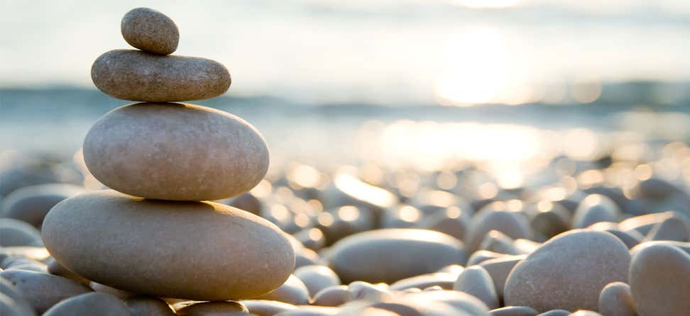 A variety of rocks are balanced vertically on the beach.