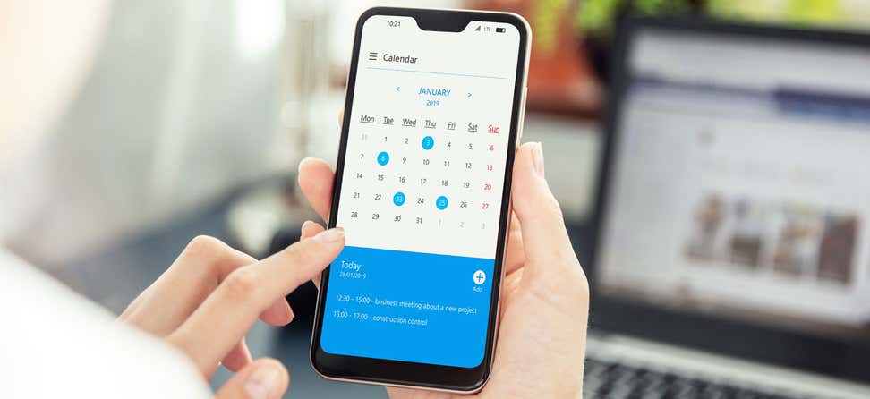 Close up shot of a person holding a cell phone, looking at their calendar trying to make a decision.