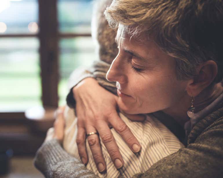 Older woman is seen embracing the senior man that she provides caregiving for.
