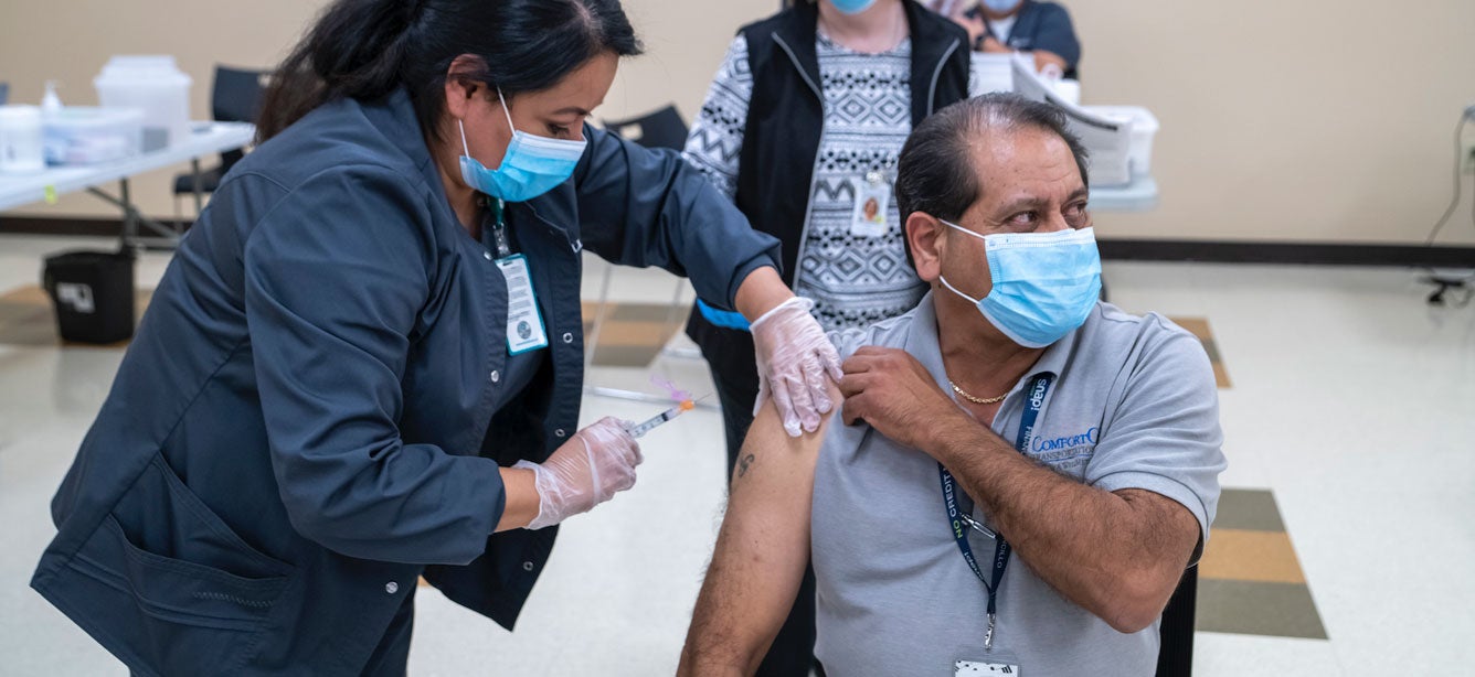 An older adult Hispanic man is receiving his COVID-19 vaccination at the Griffin Senior Center.