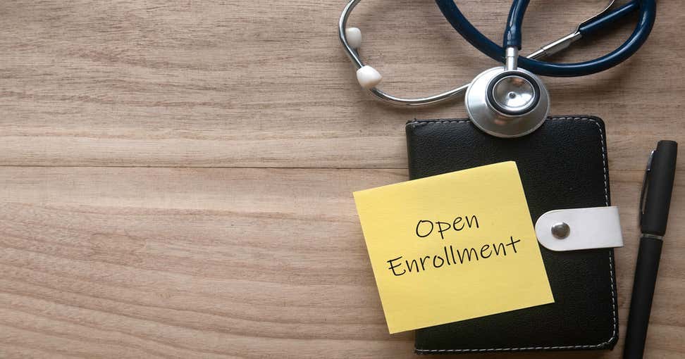 A yellow sticky note lays on top of a pad of paper, sitting next to a pen and a stethoscope.