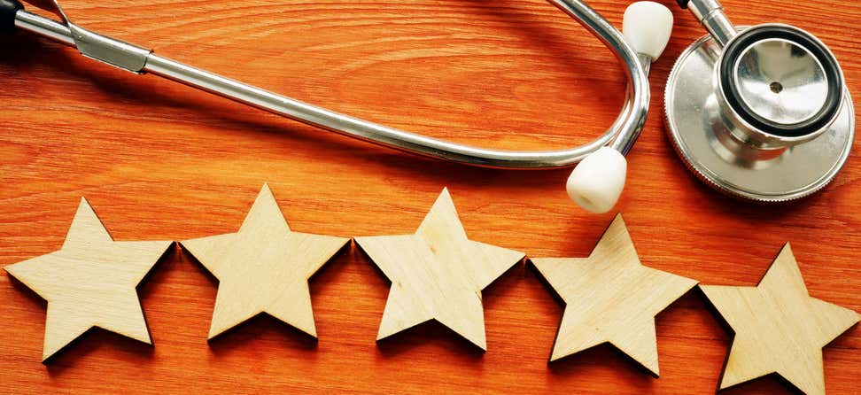 Five stars are on a table underneath a stethoscope, indicating a five star rating for a doctor or healthcare professional.