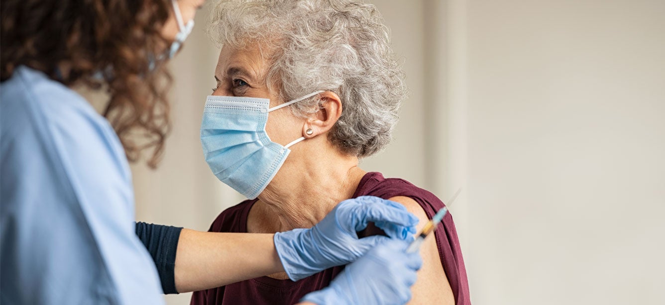 doctor gives a vaccine injection to senior woman at the hospital
