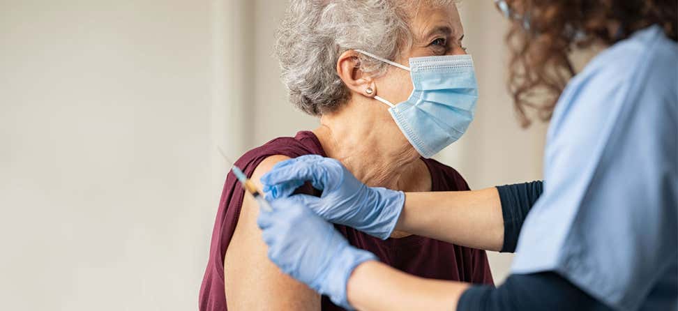 senior white woman with mask receiving covid vaccine