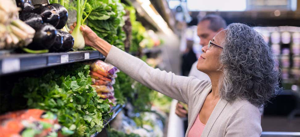 A Black woman is shopping for produce in the grocery store.