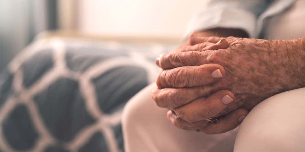 A close up shot of a senior man's hands folded on his lap.