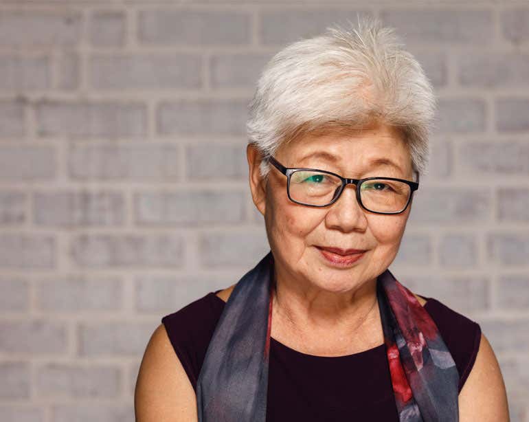 A close up, portrait shot of a senior Asian woman wearing glasses who has a concerned look on her face.