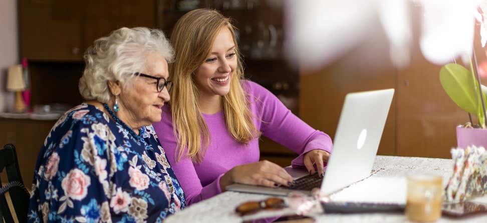 Younger woman helping older woman on laptop