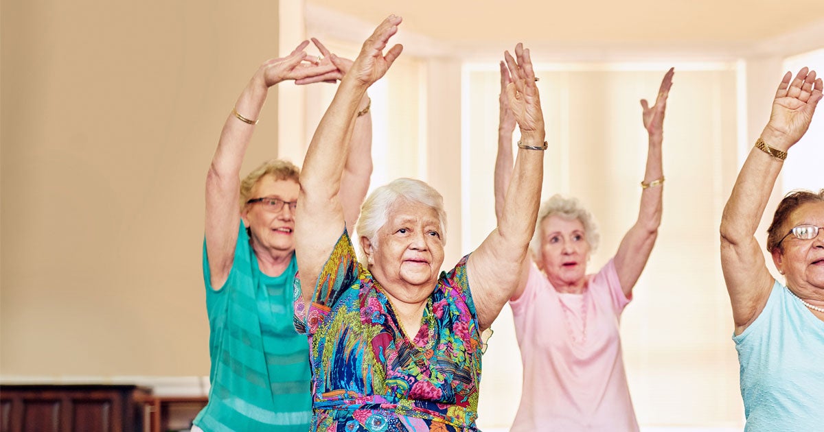 Three senior women are exercising indoors together.