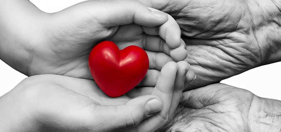 An elderly woman and her granddaughter hold a heart in their hands.