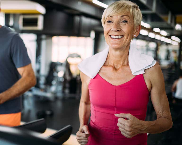 An older Caucasian woman is seen exercising on a treadmill.