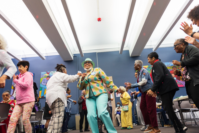 Older adults dance energetically together, celebrating at a lively event.