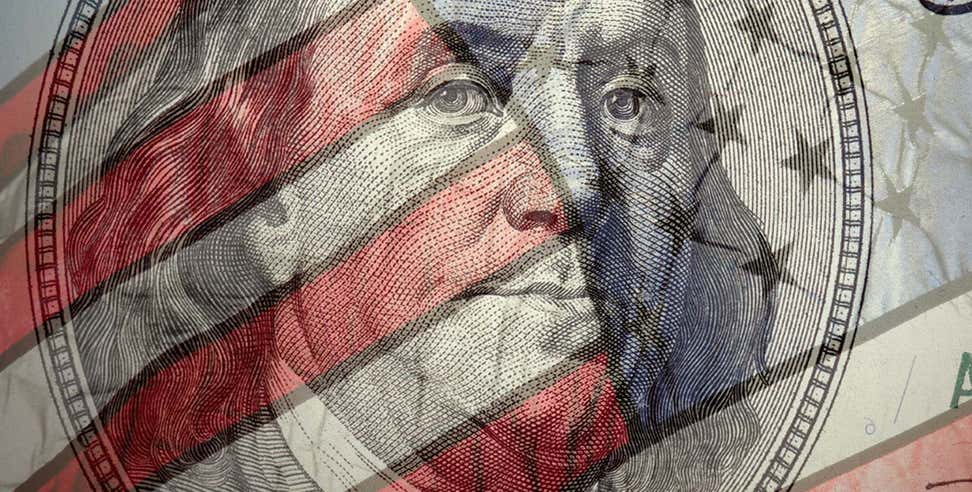 An up close shot of Benjamin Franklin on the 100 dollar bill with an overlay of the American flag.