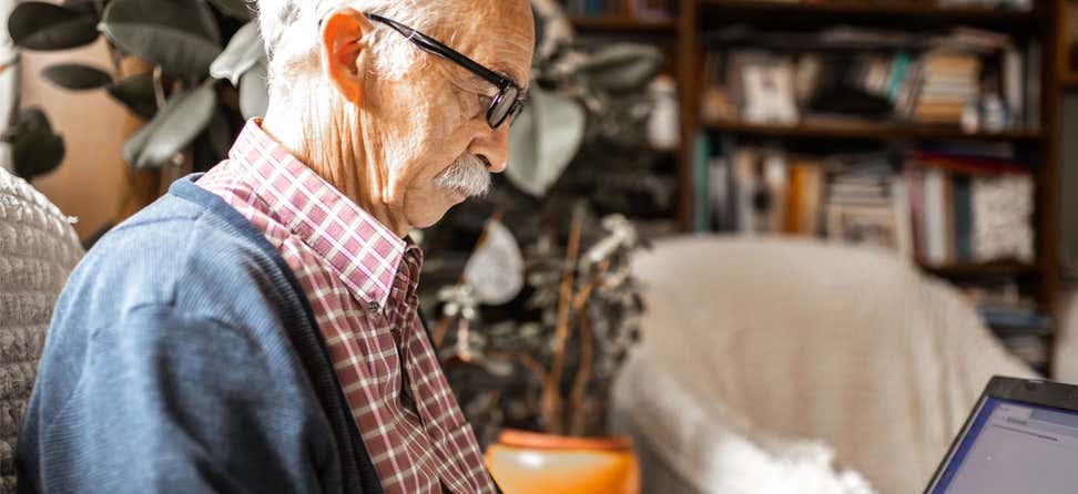 A senior man is in deep thought as he writes to a member of Congress.