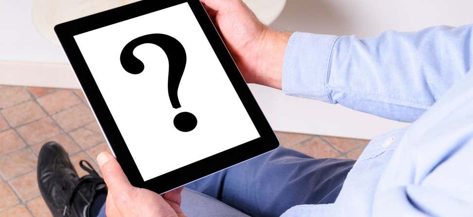 A large question mark is in the center of the screen on a digital tablet that a senior person is holding.