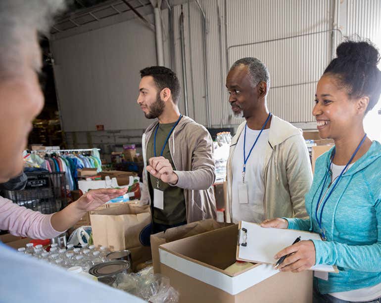 A group of intergenerational professionals are working together as a group to get food together for a food drive.